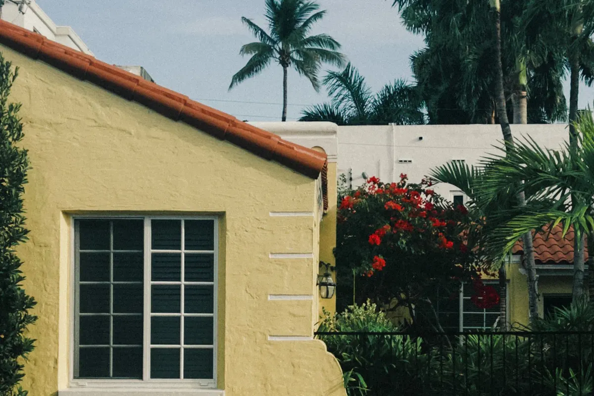 Yellow stucco house with a white grid window behind a garden wall