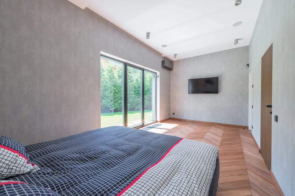 Bedroom with a wall of sliding glass doors opening onto a lawn