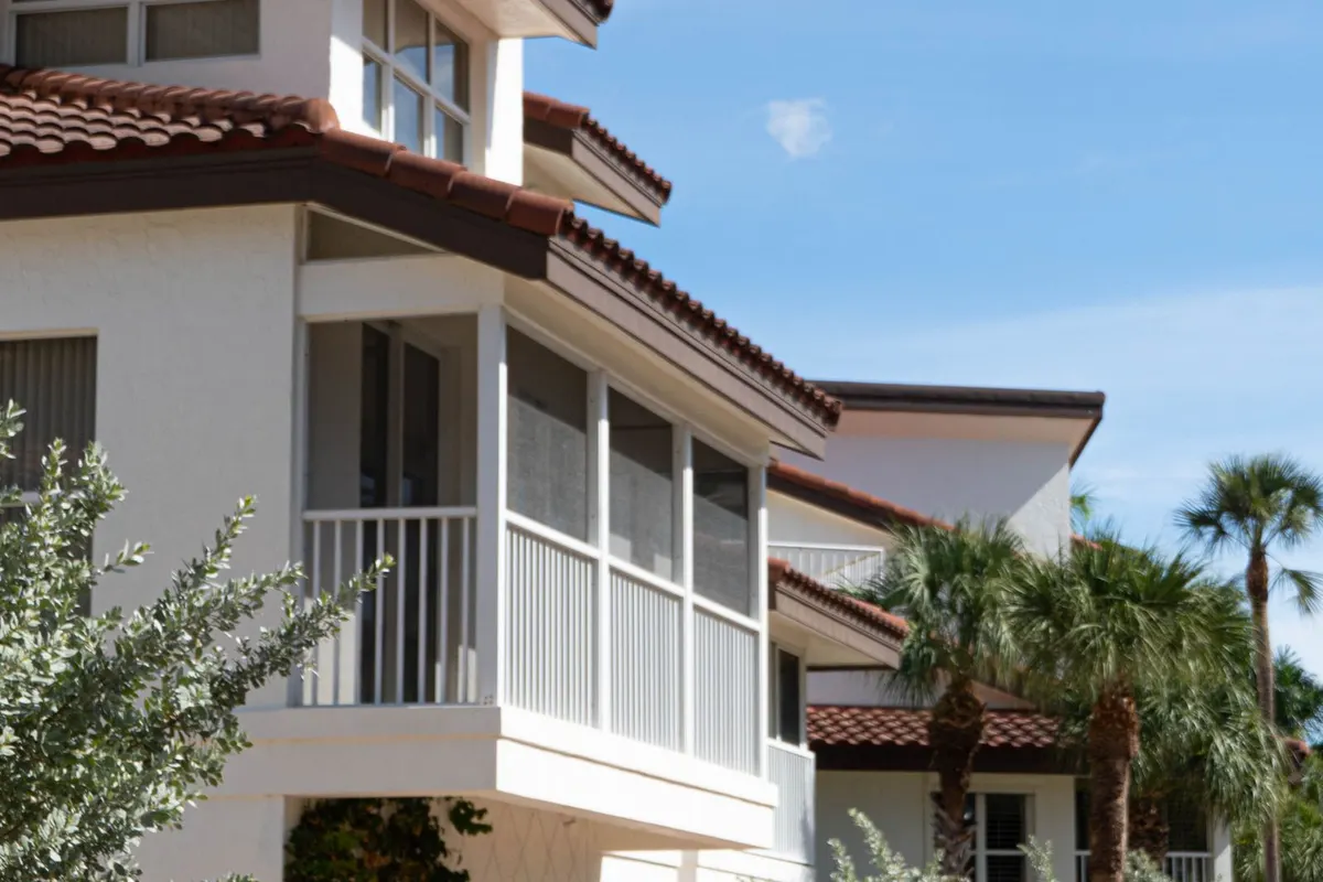 White two-story Florida home with a screened balcony and palm trees