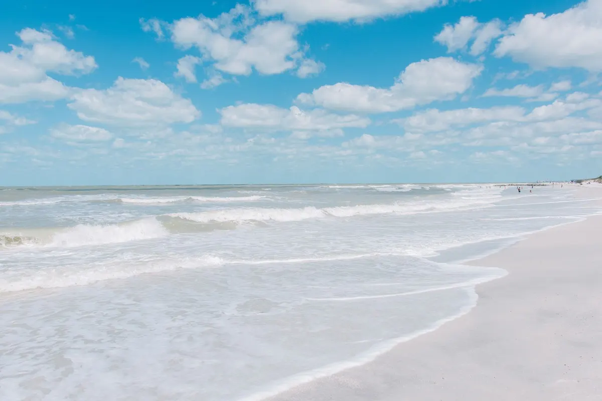 Surf rolling onto the white sand at St. Pete Beach under a blue sky